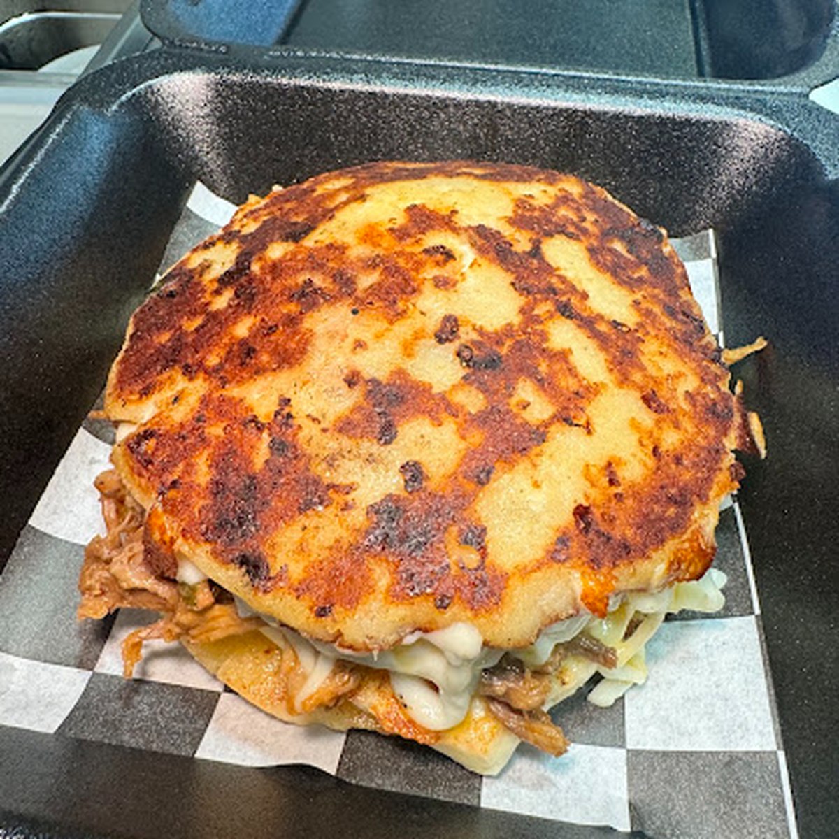 A thick arepa with melted cheese, off the flat top